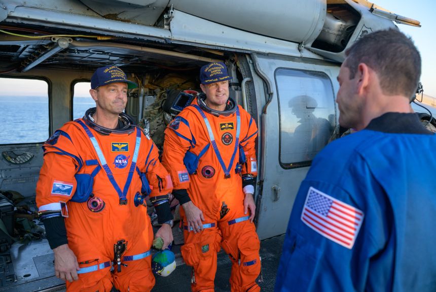 (De la stânga) Reid Wiseman de la NASA și Jeremy Hansen de la CSA vorbesc cu administratorul NASA Jared Isaacman pe puntea de zbor a USS John P. Murtha, după stropire vineri în Oceanul Pacific, în largul coastei Californiei.