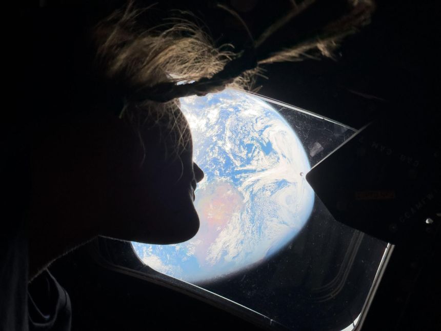 NASA astronaut Christina Koch peers out of one of the Orion spacecraft's windows, looking back at Earth.